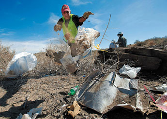 Sam Flores piles trash for pickup along North Ninth Street during a citywide community cleanup on Saturday. © 2011 Gallup Independent / Adron Gardner 
